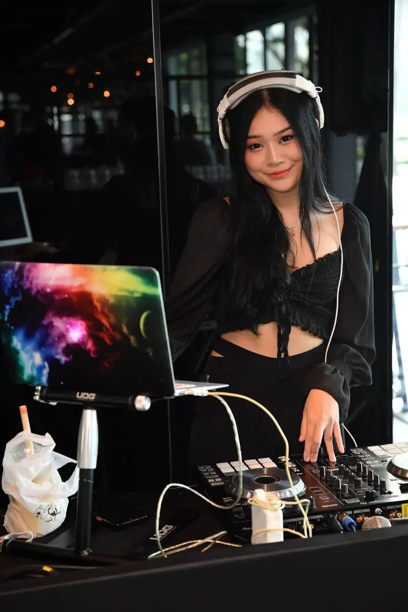 Female DJ in Singapore at a DJ booth with a laptop and controller in a bar venue