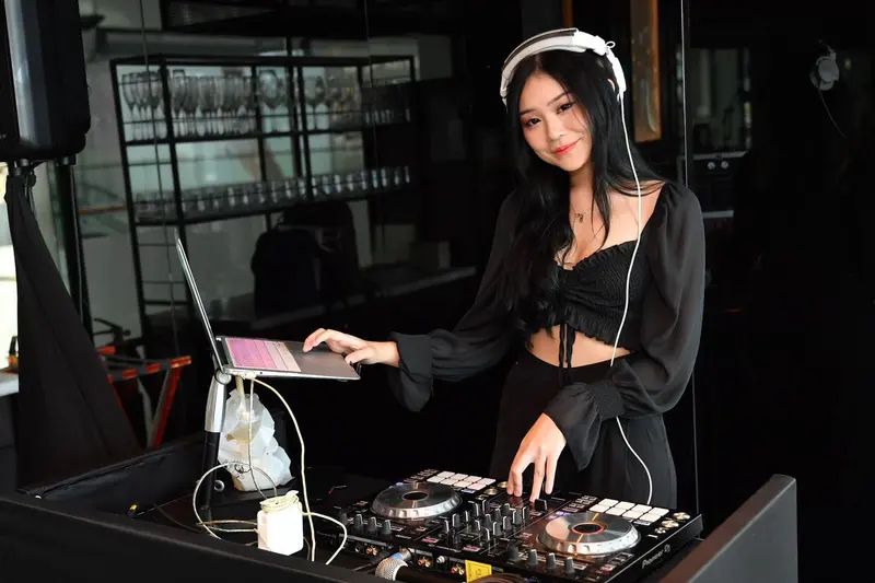 Female DJ playing a set on a DJ controller at a restaurant event in Singapore